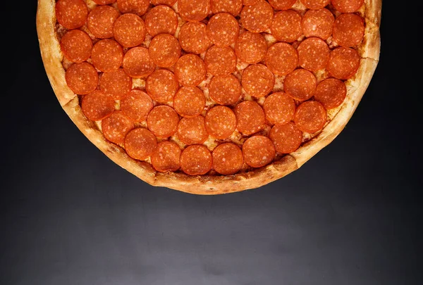 Koncepcja Pizza z kiełbasą pepperoni na czarnym tle. Widok z góry Bardzo wysokiej jakości zdjęcie. — Zdjęcie stockowe