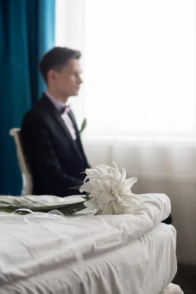 Noivo com um buquê de casamento está sentado na cadeira — Fotografia de Stock