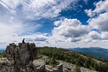 Cliff yakınındaki kayada oturma ve güzel manzaraya bakarak uzun yürüyüşe çıkan kimse