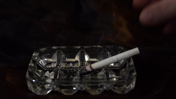 Cigarro em um cinzeiro em um fundo preto. Cinzeiro com cigarro gira — Vídeo de Stock