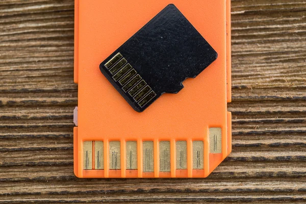 Orange memory SD card, old wood background