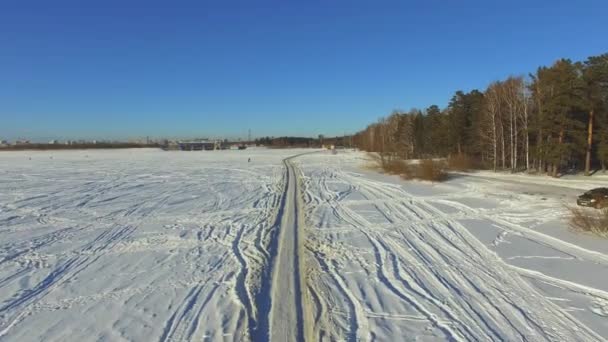 Létání nad zimní les a vozu na silnici mezi sněhem pokryté stromy během v zimě — Stock video
