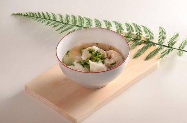 Wonton Soup Fresh Herbs with wooden coaster background and green pine needles lying on top