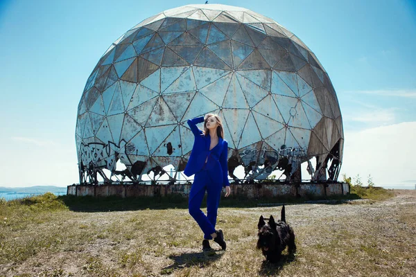 Young woman is posing in a blue casual costume in front of old dopler radar