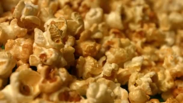 Popcorn op een groene achtergrond. Slow Motion. Close-up. Horizontale pan. 2 schoten — Stockvideo