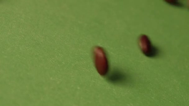 Hnědé fazole na zeleném pozadí. Zpomalený pohyb. Detail. Horizontální pánev. 2 snímky — Stock video