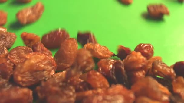 Raisins on a green background. 2 Shots. Slow motion. Horizontal pan. Close-up. — Stock Video