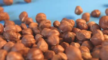 Mavi bir arka plan üzerinde fındık. 2 tekila. Ağır çekim. Yatay pan. Yakın çekim.