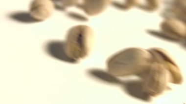 Beyaz zemin üzerine Antep fıstığı. 2 tekila. Ağır çekim. Dikey pan. Yakın çekim.