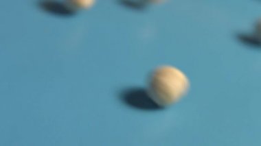 Mavi bir arka plan üzerine Antep fıstığı. 2 tekila. Ağır çekim. Dikey pan. Yakın çekim.