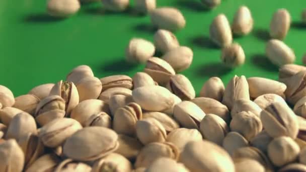 Pistachios on a green background. 2 Shots. Slow motion. Horizontal pan. Close-up. — Stock Video