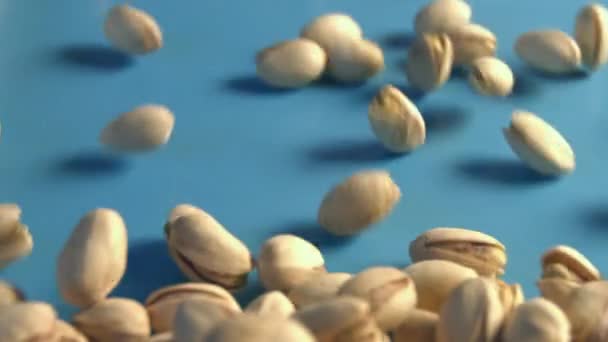 Pistachios on a blue background. 2 Shots. Slow motion. Vertical pan. Close-up. — Stock Video