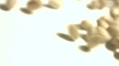 Beyaz zemin üzerine Antep fıstığı. 2 tekila. Dikey pan. Yakın çekim.