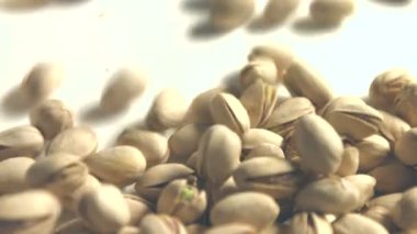 Beyaz zemin üzerine Antep fıstığı. 2 tekila. Dikey pan. Yakın çekim.