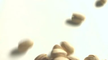 Beyaz zemin üzerine Antep fıstığı. 2 tekila. Dikey pan. Yakın çekim.