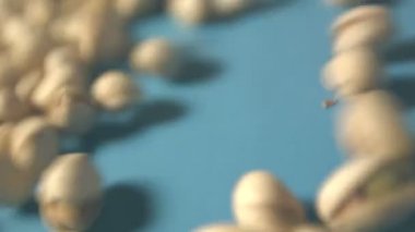 Mavi bir arka plan üzerine Antep fıstığı. 2 tekila. Dikey pan. Yakın çekim.