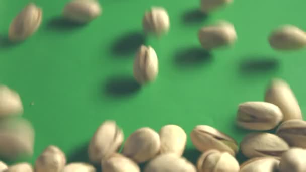 Pistachos sobre fondo verde. Dos disparos. Sartén vertical. Primer plano . — Vídeo de stock