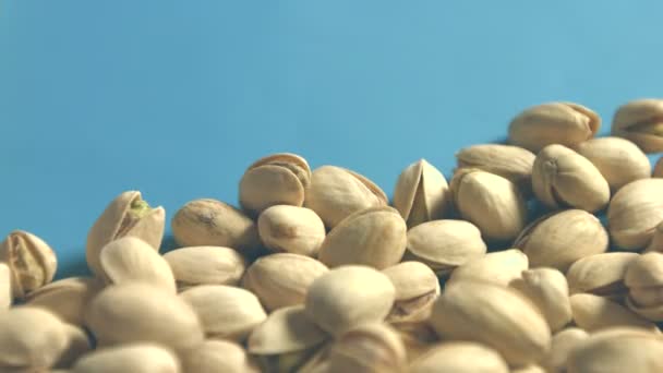 Pistachios on a blue background. 2 Shots. Horizontal pan. Close-up. — Stock Video