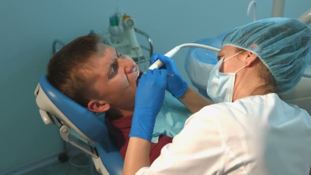 Der Zahnarzt behandelt die Zähne eines jungen Mannes. 2 Schüsse — Stockvideo