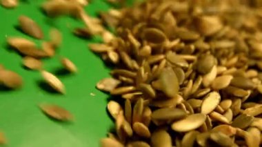 Yeşil bir arka plan üzerinde kabak çekirdeği kabuklu. Ağır çekim. Yakın çekim. Yatay pan. 2 çekim