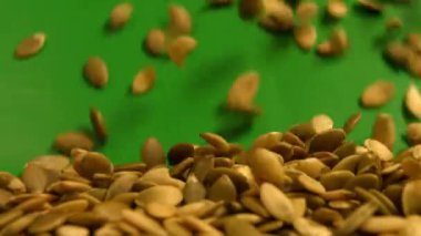 Yeşil bir arka plan üzerinde kabak çekirdeği kabuklu. Ağır çekim. Yakın çekim. Yatay pan. 2 çekim