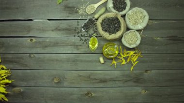 Ayçiçeği yağı ve tohumlar eski ahşap bir masada. Üst Manzara. Masanın üzerinde tohum çuvalları (soyulmuş ve soyulmamış) ve ayçiçeği yağı vardır. Masa ayçiçekleri ve taç yapraklarıyla süslenmiş..