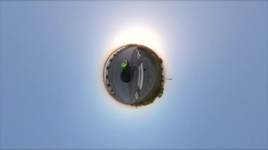 Bisiklet sürmek. Küçük gezegen. 360 derece kamera. Bisikletçi yol boyunca gezer. Güneş ufkun ötesinde batıyor. İyi akşamlar..