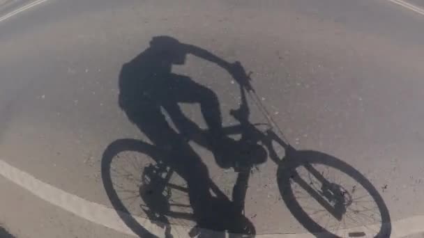 자전거타기 그림자 아스팔트에 자전거타는 사람의 그림자 도로에서 운전을 합니다 — 비디오