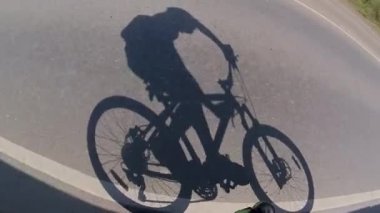 Bisiklet sürmek. Gölge. Asfalttaki bisikletçinin gölgesi. Otoyolda gidiyor..