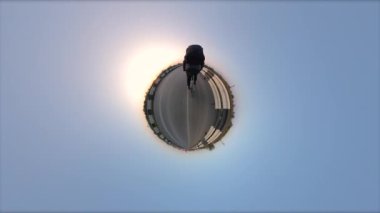 Bisiklet sürmek. Küçük bir gezegen manzarası. 360 derece kamera. Bisikletçi otoyolda gidiyor. Güneş ufkun ötesinde batıyor. İyi akşamlar..