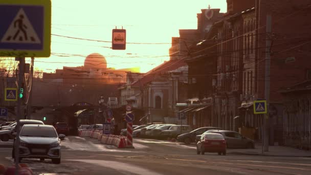 日没の街の通り 動きを2倍にします 旧市街中心部 太陽は家の間に沈む 通りは閑散としている 道路の脇に車が停まっている 一台の車が道路を走っている — ストック動画