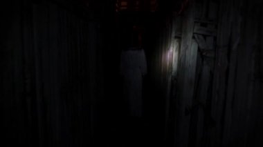 Yeraltında bir kadın. Beyaz elbiseli bir kadın karanlıkta uzun bir koridorda yürüyor. Bir el feneri onu arkadan aydınlatıyor..