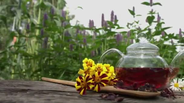 茶在自然界 玫瑰花瓣 金盏花和洋甘菊都在一张破旧的木制桌子上 相机平滑的水平运动 — 图库视频影像