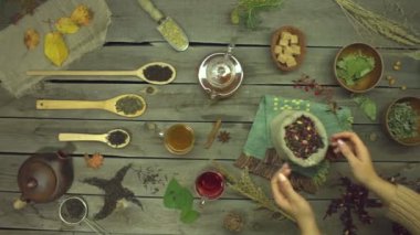 Eski ahşap bir masanın üzerindeki gül yapraklarından yapılan kırmızı çay. Düz yatıyordu. Değişik çay çeşitleriyle yaşam: siyah, yeşil, eş, amber çiçeği, çiçek, meyve, bitki. Kadın elleri masadan bir paket amber çayı alır. Yavaş çekim 2x.