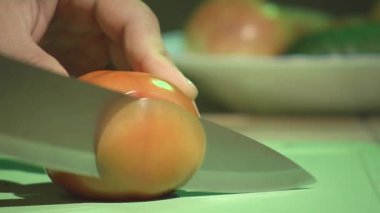 Bir kesme tahtası üzerinde bir domates kesme.