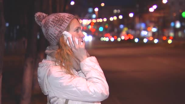 Girl talking on the phone in the evening on the street. Rejoice, smiling. — Stock Video