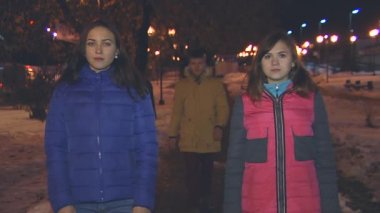 İki kız ayakta, çocuk geri gelir ve aralarında alır.
