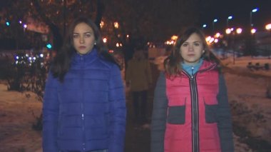 İki kız ayakta, çocuk geri gelir ve aralarında alır.