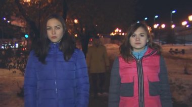 İki kız ayakta, çocuk geri gelir ve aralarında alır.