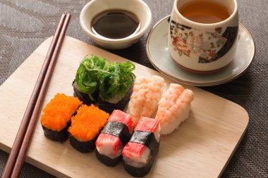 Sushi set with chop sticks and soy sauce served on wooden slate  clipart