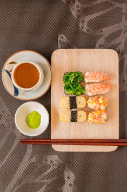 Sushi set with chop sticks, wasabi served on wooden slate, selec clipart