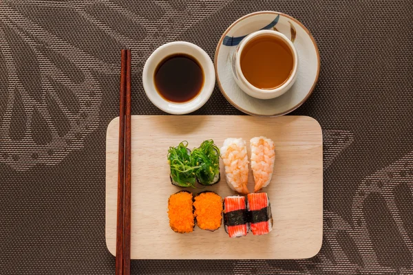 Sushi set dengan chop stick dan kecap disajikan pada batu tulis kayu — Stok Foto