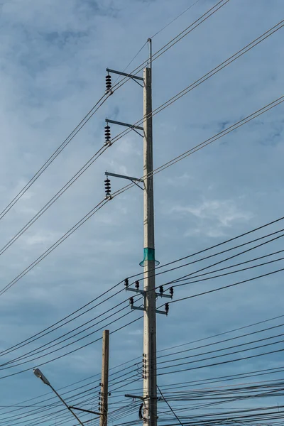 Ηλεκτρικό πόλων και ηλεκτρικής ενέργειας γραμμή με ενάντια μπλε συννεφιασμένο ουρανό, — Φωτογραφία Αρχείου