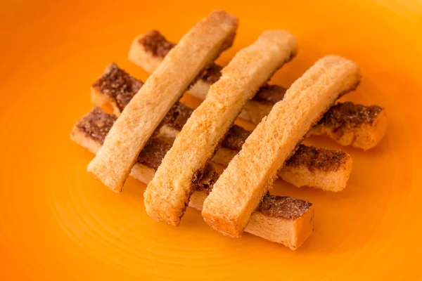 Sliced crispy bread in orange ceramic dish. — Stock Photo, Image