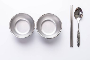 Beyaz arka planda iki küçük alüminyum kaseler, kaşıklar ve çubuklar.. 