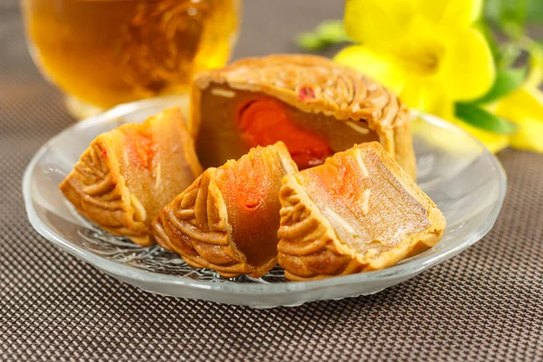 Lezzetli mooncake ve sıcak çay ile sarı çiçek öğeleri.
