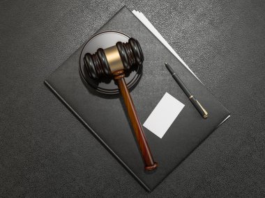 Wooden judges gavel and leather folder on black leather desk