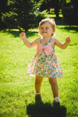 Küçük kız çimenlerde oynuyor.