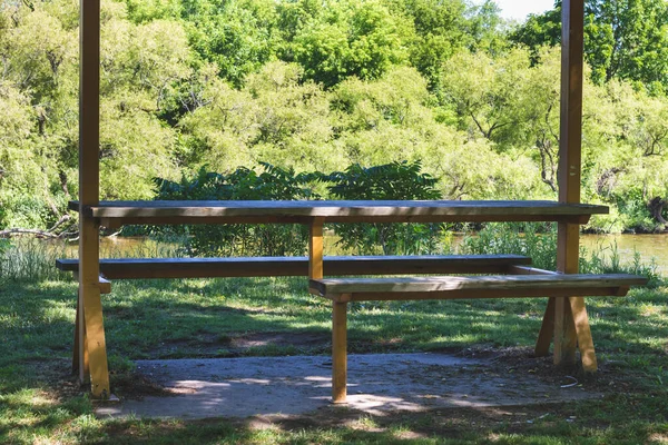 Tekerlekli sandalye erişilebilir ahşap piknik masası. Arka planda ağaçlar.