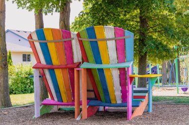 Bir çocuğun oyun parkındaki iki büyük Adirondack sandalyesinin arka görünümü.